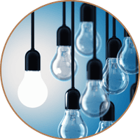 A group of lightbulbs hang on black cords. One lightbulb is lit symbolizing clarity. 