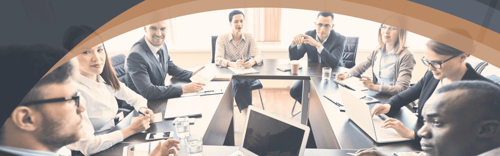 Team members working together around a table with computers in a collaborative workspace, symbolizing Optimum Transitions' experienced advisors and trusted partners dedicated to business transition guidance