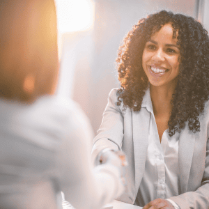 Two professionals shaking hands in business attire, representing Optimum Transitions' core value of putting clients' goals and interests first in every advisory relationship