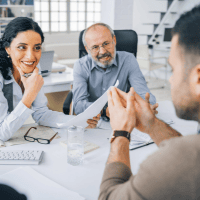 a group of people sitting around a table in an office representing Optimum Transitions' core value of putting clients first